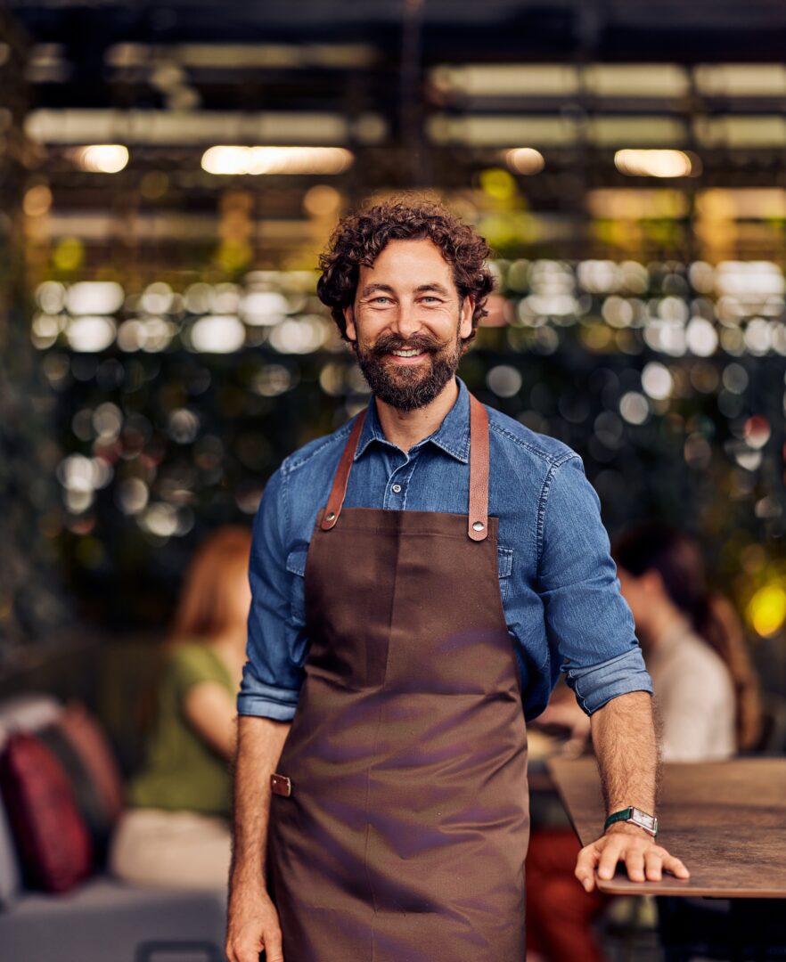 Friendly,Café,Owner,In,Apron,Standing,Confidently,In,Charming,Outdoor